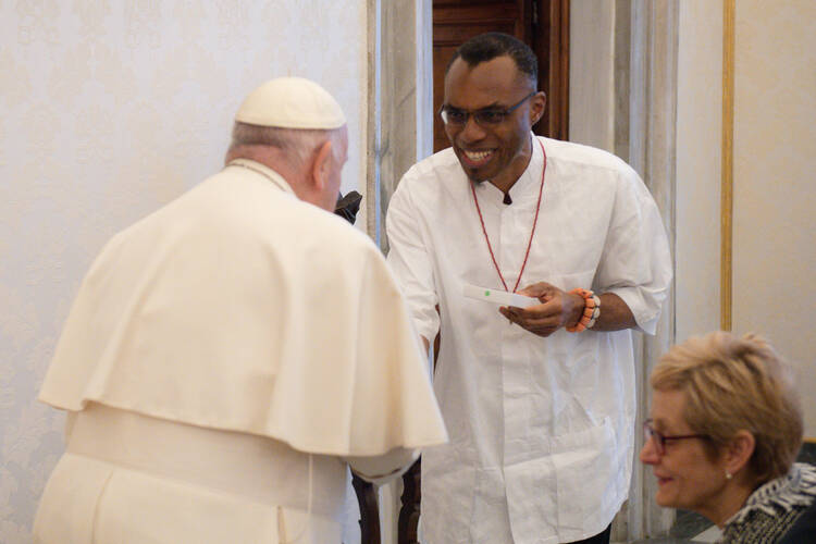Pope Francis greets Agbonkhianmeghe Orobator, S.J., and Julie Sullivan, the president of Santa Clara University, on March 18, 2024. 