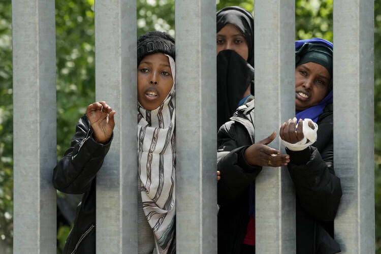 A view of migrants behind the metal barrier border that Poland has erected along the border with Belarus, in Bialowieza Forest, on May 29. Poland says neighboring Belarus and its main supporter Russia are behind a surging push by migrants in Belarus toward the European Union. (AP Photo/Czarek Sokolowski)