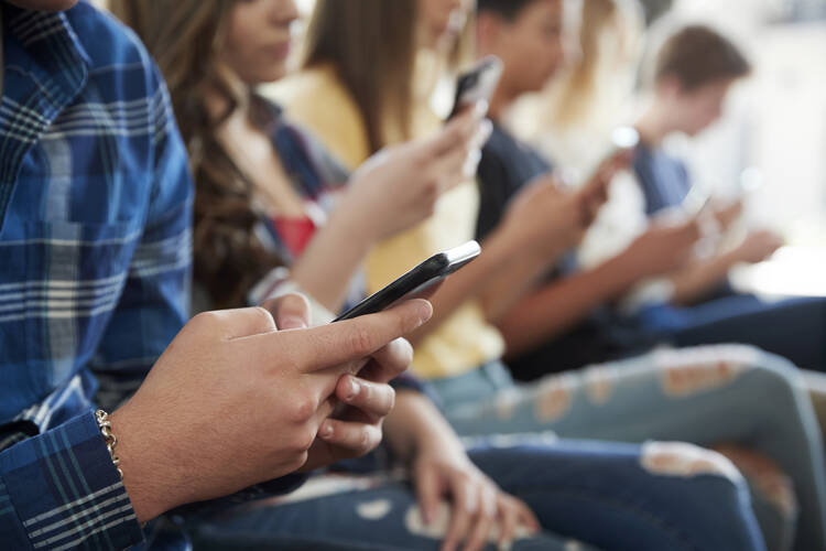 U.S. teens spend an average of 4.8 hours a day on social media, according to a Gallup poll. Photo shows teenagers seated in a row, all looking at their phones. (iStock/monkeybusinessimages)