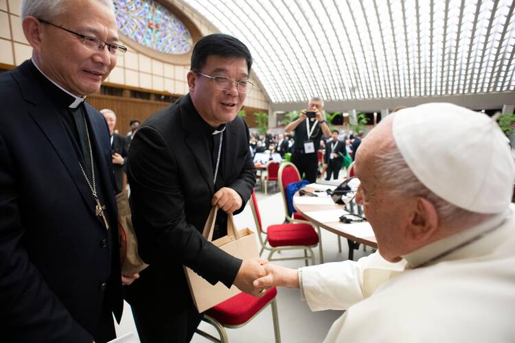 Bishop Joseph Yang Yongqiang of Hangzhou, China, shakes hands with Pope Francis while Bishop Vincent Zhan Silu of Funing-Mindong, the other member of the Synod of Bishops from mainland China, looks on in the Paul VI Audience Hall 