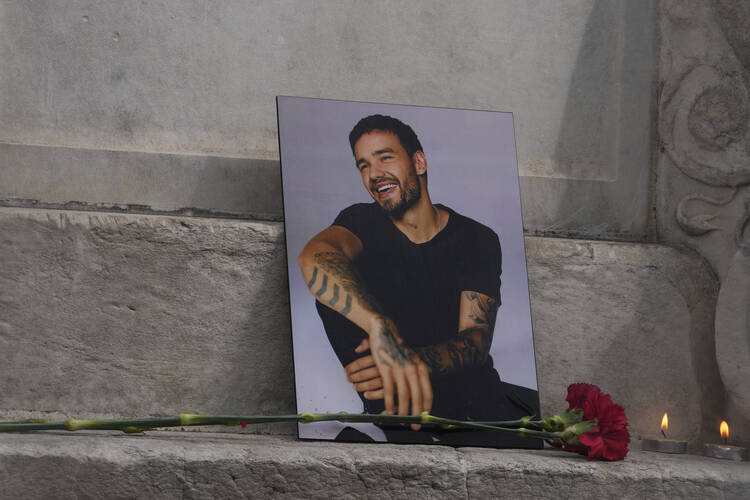 A photo of former One Direction singer Liam Payne is placed with a rose and candles as fans gather in Madrid, Spain, Sunday, Oct. 20, 2024, after the British pop singer fell to his death from a hotel balcony in Argentina. 