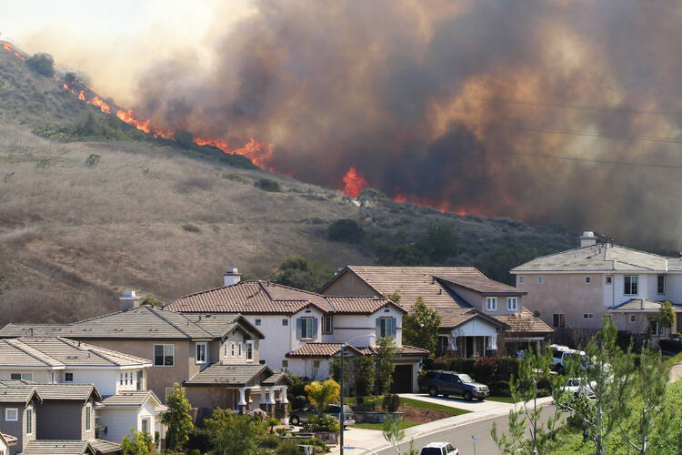 A brushfire on a hill threatens a row of single-family homes, below, in Southern California. (iStock/f00sion)