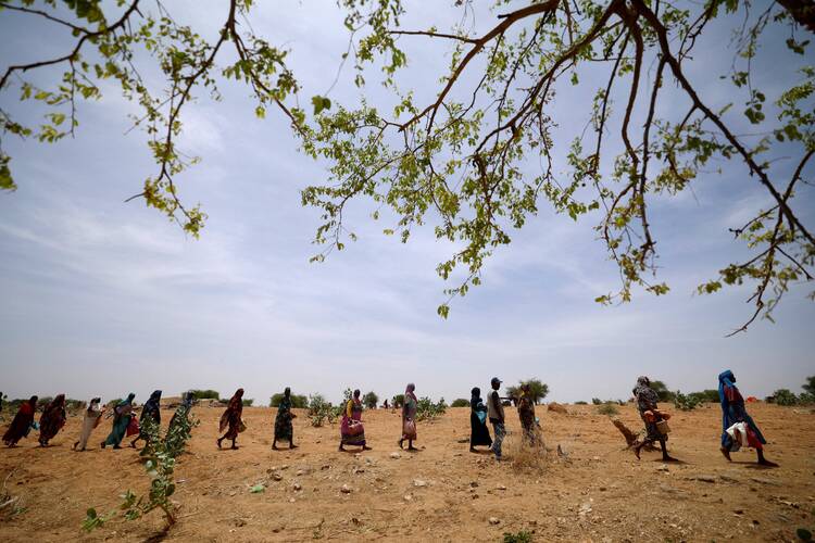 Sudanese refugees who have fled the violence in their country walk in line in the desert in Koufroun, Chad, to receive food rations in May 2023. (OSV News photo/Zohra Bensemra, Reuters)