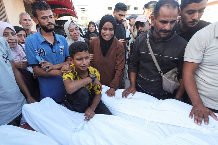 A boy mourns over the body of his father and other Palestinians at Al-Aqsa Martyrs Hospital in Deir Al-Balah in the central Gaza Strip Oct. 9, 2024. They were killed in an Israeli strike amid the ongoing Israel-Hamas war. (OSV News photo/Ramadan Abed, Reuters)