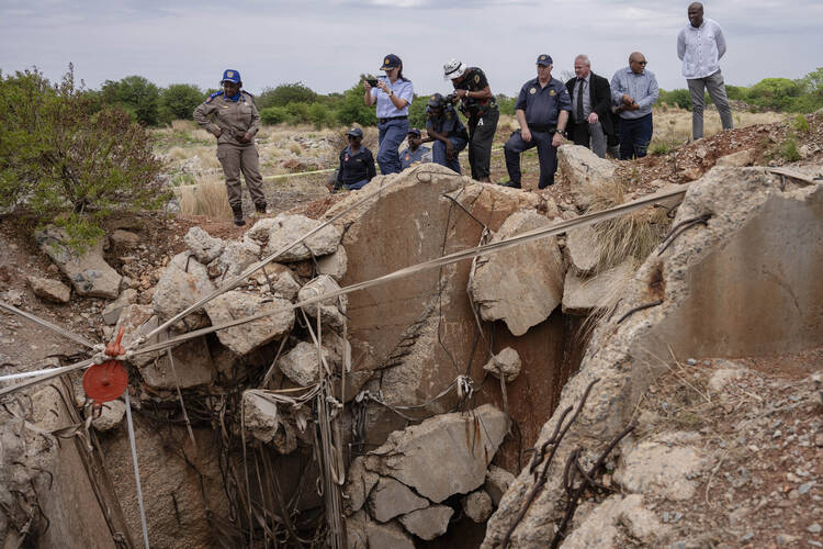 Authorities in Stilfontein, South Africa, survey the entrance to an abandoned mine shaft, part of a police effort to bring miners below to the surface on Nov. 15. Photo by Ihsaan Haffejee/GroundUp (CC BY-ND 4.0).