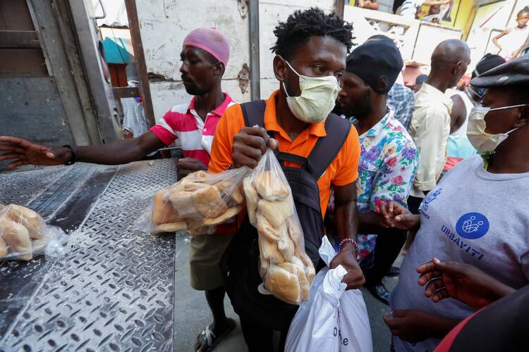 People accept food distributed from a truck by a Haitian government program in Port-au-Prince, Haiti, April 6, 2020, amid the coronavirus (COVID-19) pandemic. The U.S. Conference of Catholic Bishops and other faith groups then were urging the Trump administration to support debt relief for poor nations. (CNS photo/Jeanty Junior Augustin, Reuters)