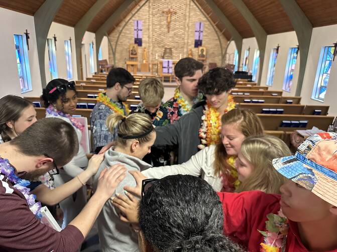 Students and adult leaders pray over English teacher Jen Morris on a Kairos retreat at Brebeuf Jesuit Preparatory School in Indianapolis (Amanda Murphy)