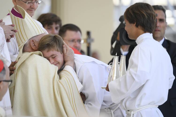 Pope Francis shares a hug with Jerome, one of two altar servers with Down syndrome at the Mass at the close of World Youth Day in Lisbon, Portugal, on Aug. 6, 2023. (CNS photo/Vatican Media)
