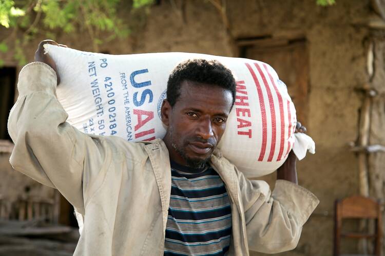 A man carries a bag of wheat supplied by Catholic Relief Services and USAID for emergency food assistance in a village near Shashemane, Ethiopia, in this 2016 photo. (CNS Photo/Nancy McNally, Catholic Relief Services)