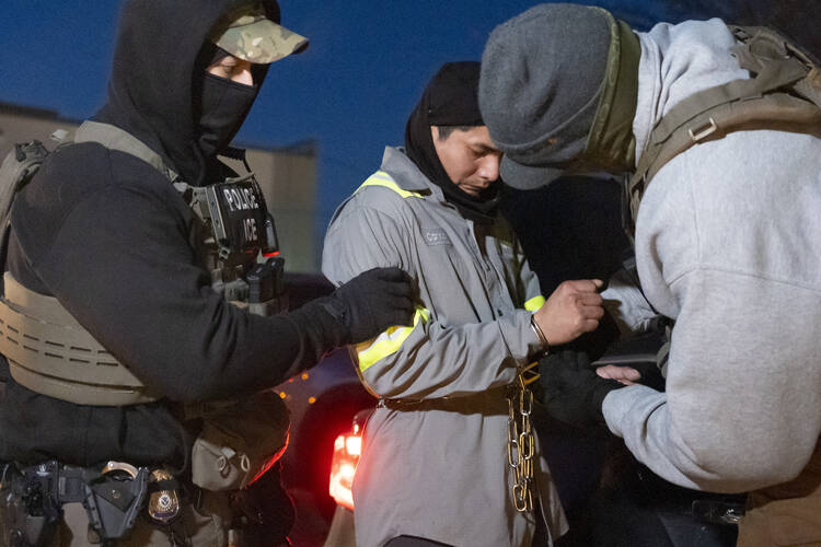 U.S. Immigration and Customs Enforcement officers attach a chain to a detained person on Jan. 27 in Silver Spring, Md. (AP Photo/Alex Brandon)