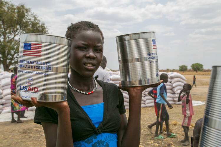 A woman holds cans of vegetable oil provided by U.S. Agency for International Development in Pajut, South Sudan, in this 2017 photo. Catholic Relief Services provided food assistance, with U.S.A.I.D. funding, to communities and people who returned to the area after being displaced during violence in 2013. (CNS photo/Nancy McNally, Catholic Relief Services)