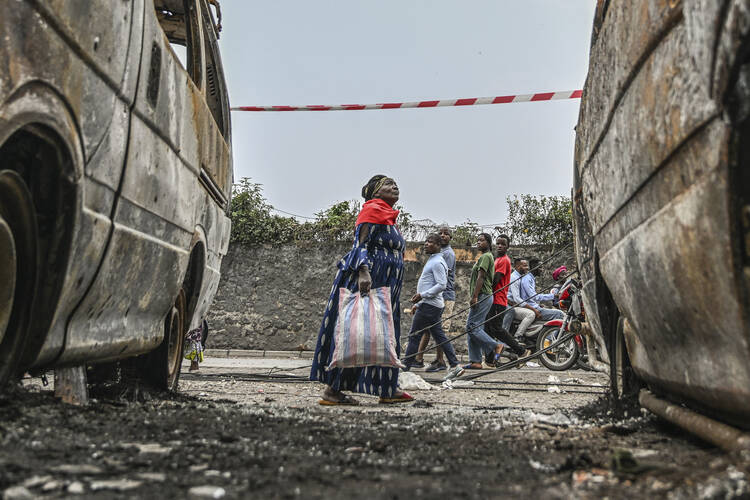 Residents walk by charred vehicles in Goma, Democratic Republic of the Congo, on Jan. 31. (AP Photo/Moses Sawasawa)