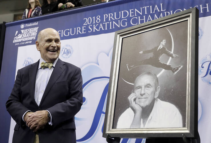 Dick Button smiles next to a painting of him while honored at the U.S. Figure Skating Championships in San Jose, Calif., Thursday, Jan. 4, 2018. (AP Photo/Marcio Jose Sanchez, File)