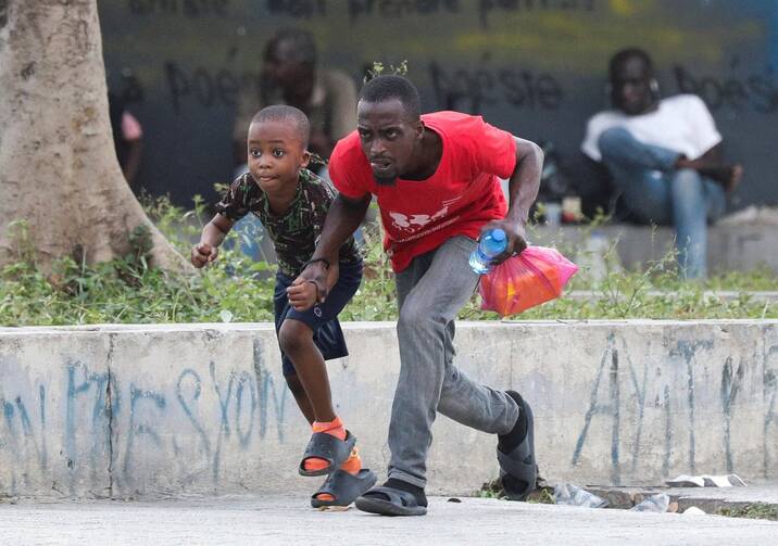 A man and child take cover from gunfire near the National Palace in Port-au-Prince, Haiti, March 21, 2024. (OSV New photo/Ralph Tedy Erol, Reuters)