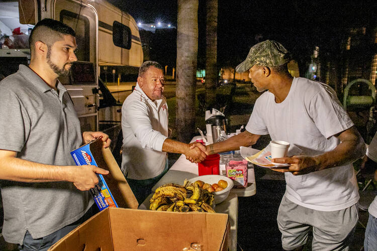 Two male "Lights On" volunteers distribute food to recently released prison inmates. (IStock/:pandapix)