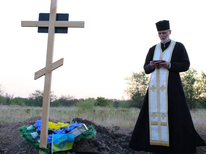 Metropolitan Archbishop Borys A. Gudziak of the Ukrainian Catholic Archeparchy of Philadelphia prays at the grave of a fallen Ukrainian soldier at a military cemetery near the city of Zaporizhzhia, Ukraine, Sept. 6, 2024. (OSV News photo/Gina Christian)