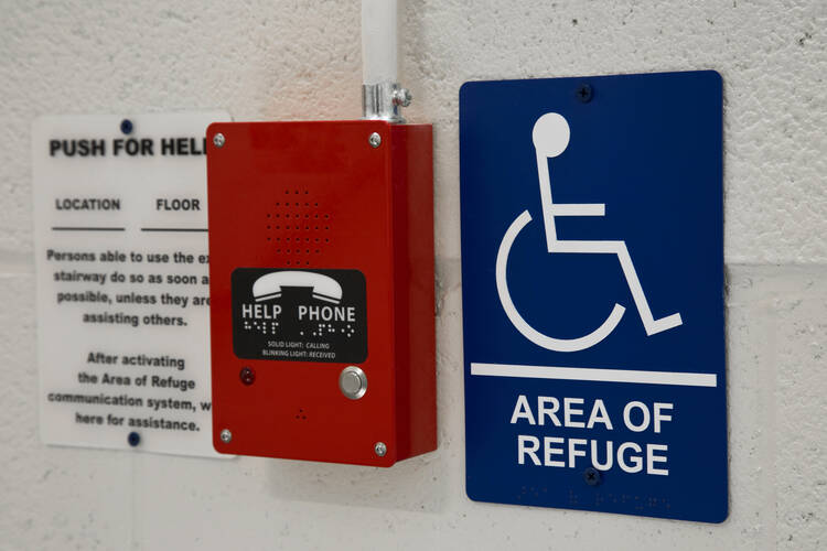 Photo of red "help" phone attached to wall next to sign depicting a wheelchair and marked "Area of Refuge" (iStock/Johnrob)
