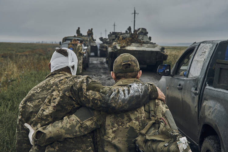 A Ukrainian soldier helps a wounded comrade on the road in reclaimed territory in the Kharkiv region, Ukraine, on Sept. 12, 2022. (AP Photo/Kostiantyn Liberov, File)