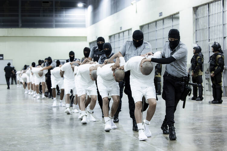 n this photo provided by El Salvador's presidential press office, prison guards transfer deportees from the U.S., alleged to be Venezuelan gang members, to the Terrorism Confinement Center in Tecoluca, El Salvador, Sunday, March 16, 2025. (El Salvador presidential press office via AP)