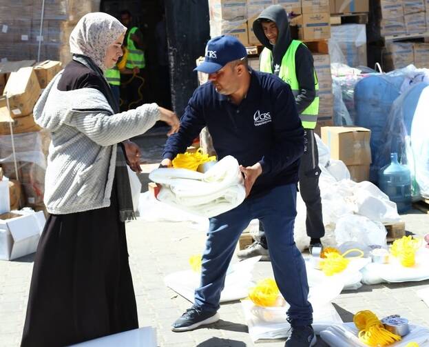 A Catholic Relief Services worker distributes shelter material to a woman in Rafah, in the southern Gaza Strip, March 21, 2024, displaced by the ongoing conflict between Israel and Hamas. (OSV News photo/Mohammad Al Hout for CRS)