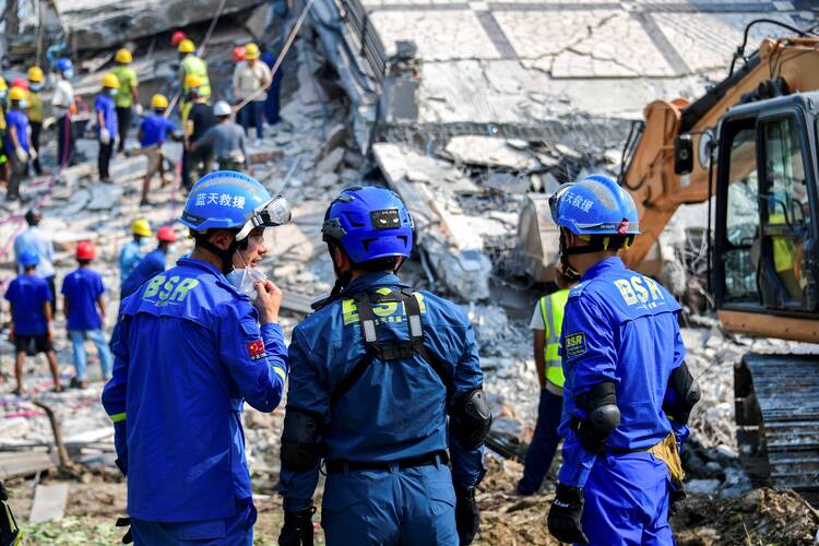 Chinese rescue workers stand at the site of a collapsed building in Mandalay, Myanmar, March 31, 2025, in the aftermath of a strong earthquake that struck three days earlier. People in Myanmar are in desperate need of humanitarian supplies and medical support as the death toll from the devastating earthquake that rocked central Myanmar continues to rise. (OSV News/Reuters)