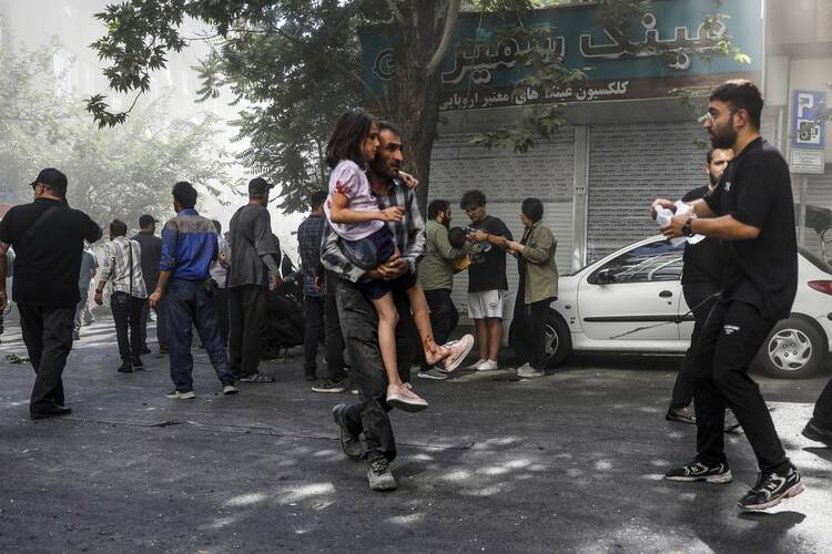 A man carries a wounded girl after an explosion in downtown Tehran amid Israel's three-day campaign of strikes against Iran, Sunday, June 15, 2025. (AP Photo/Morteza Zangene/ISNA)