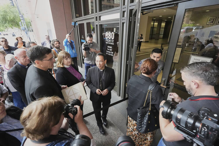 Bishop Micheal Pham, center, leads an inter-faith group as they enter a federal building to be present during immigration hearings on June 20 in San Diego. (AP Photo/Gregory Bull)