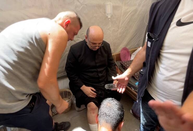 Parish priest of the Holy Family Parish, Father Gabriel Romanelli, receives medical attention, after he suffered light leg injuries following what initial reports said was an Israeli tank attack on the church, according to initial reports, at Al-Ahli Arab Hospital in Gaza City, in this still image taken from a video July 17, 2025. (OSV News/Dawoud Abu Alkas, Reuters)