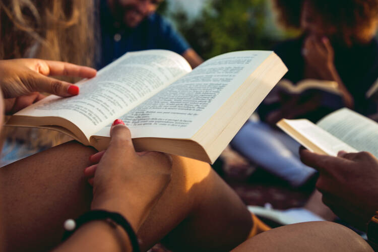 A pair of hands opening a thick paperpack book. (iStock/LeoPatrizi)