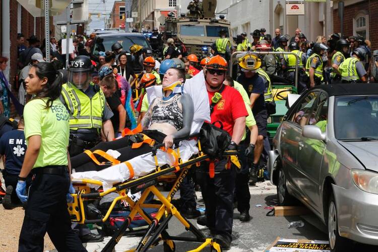 Rescue personnel help injured people after a car ran into a large group of protesters after a white nationalist rally in Charlottesville, Va., on Aug. 12, 2017. One person was killed and 19 were injured in the incident. (AP Photo/Steve Helber)