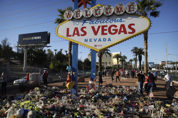 Flowers, candles and other items surround the famous Las Vegas sign at a makeshift memorial for victims of a mass shooting (AP Photo/John Locher).