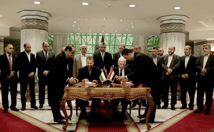 Senior Fatah official Azzam al-Ahmad, center right, and Hamas' representative, Saleh al-Arouri, center left, sign a reconciliation agreement during a press conference at the Egyptian intelligence complex in Cairo, Egypt, Thursday, Oct. 12, 2017. Thursday's signing came after two days of negotiations in the Egyptian capital on the governing of the Gaza Strip as part of the most serious effort to date to end the 10 year rift between the rival Palestinian groups. (AP Photo/Nariman El-Mofty)