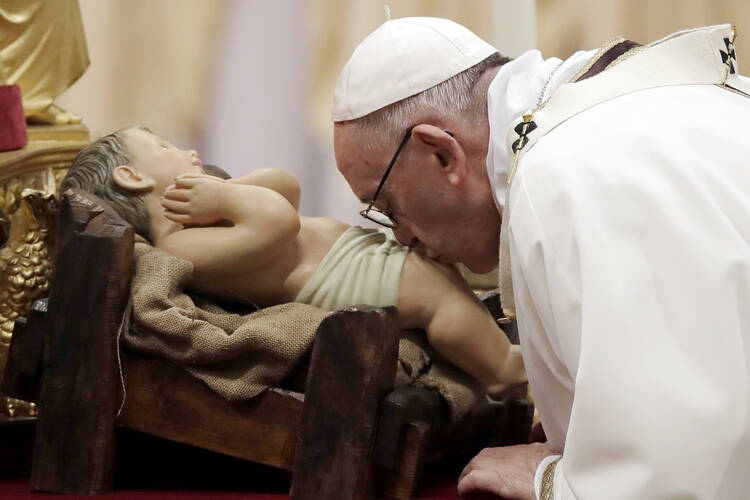 Pope Francis kisses a statue of Baby Jesus as he celebrates the Christmas Eve Mass in St. Peter's Basilica at the Vatican, Sunday, Dec. 24, 2017. (AP Photo/Alessandra Tarantino)