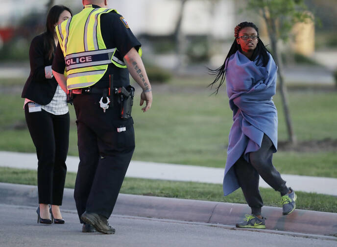 An employee wrapped in a blanket talks to a police officer after she was evacuated at a FedEx distribution center where a package exploded on March 20, 2018, in Schertz, Texas. (AP Photo/Eric Gay)