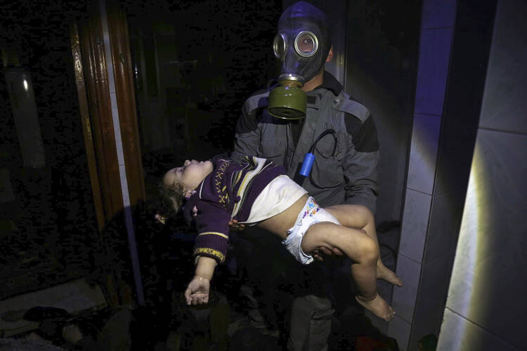 A rescue worker carries the body of a child killed during a suspected chemical weapons attack in Douma, Syria (AP Photo).