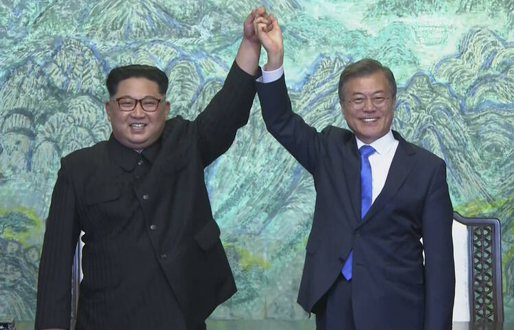 In this image made from video provided by Korea Broadcasting System (KBS), North Korean leader Kim Jong Un, left, and South Korean President Moon Jae-in raise their hands after signing on a joint statement at the border village of Panmunjom in the Demilitarized Zone Friday, April 27, 2018. (Korea Broadcasting System via AP)