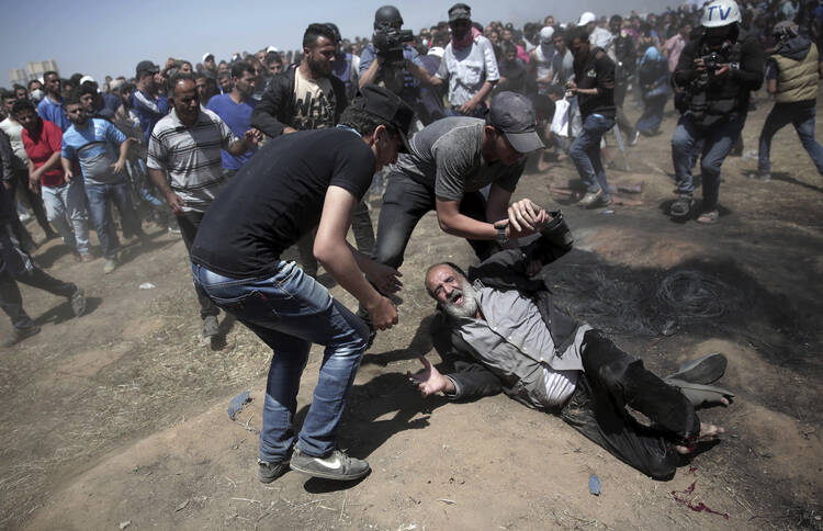 An elderly Palestinian man falls on the ground after being shot by Israeli troops during a deadly protest at the Gaza Strip's border with Israel on May 14. Thousands of Palestinians are protesting near Gaza's border with Israel, as Israel celebrates the inauguration of a new U.S. Embassy in contested Jerusalem. (AP Photo/Khalil Hamra)