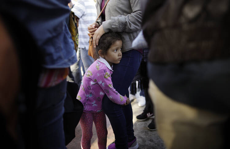 Nicole Hernandez, of the Mexican state of Guerrero, holds on to her mother as they wait with other families in Tijuana, Mexico, on June 13 to request political asylum in the United States. (AP Photo/Gregory Bull, file)