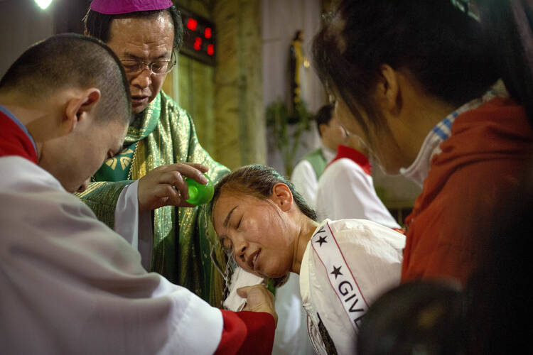 Chinese Bishop Joseph Li Shan baptizes a woman during a Mass at the Cathedral of the Immaculate Conception, a government-sanctioned Catholic church in Beijing, on Sept. 22. (AP Photo/Mark Schiefelbein, File)