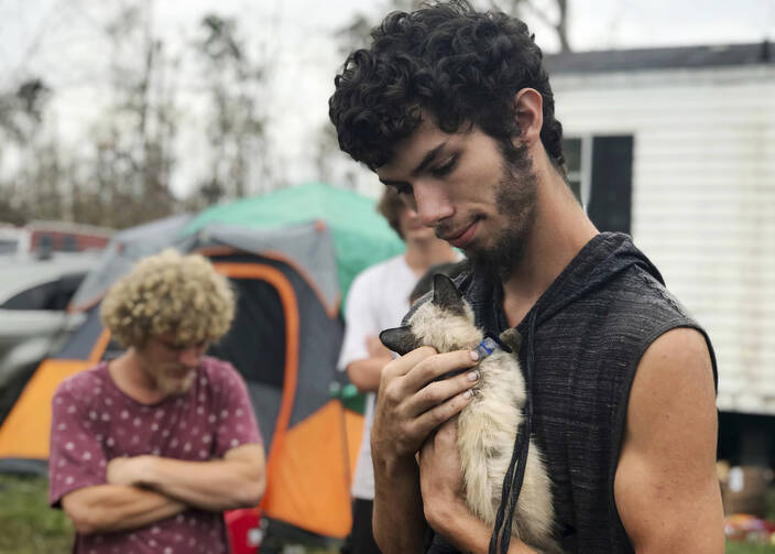 In this Oct. 23, 2018 photo, Ronald Lauricella cradles a kitten in his front yard in Bay County, Fla. The rural Bay County resident says some on the outskirts of the cities aren't getting needed services like electricity as fast as the populated areas. (AP Photo/Tamara Lush)