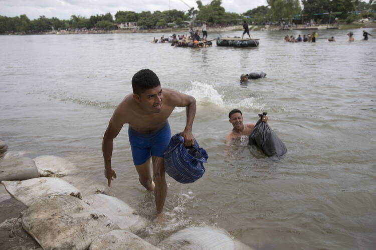 Central American migrants reach the shore on the Mexican side of the Suchiate River after wading across from Guatemala on Oct. 20. Thousands of migrants from El Salvador, Honduras and Guatemala are making their way north through Mexico. (AP Photo/Moises Castillo)