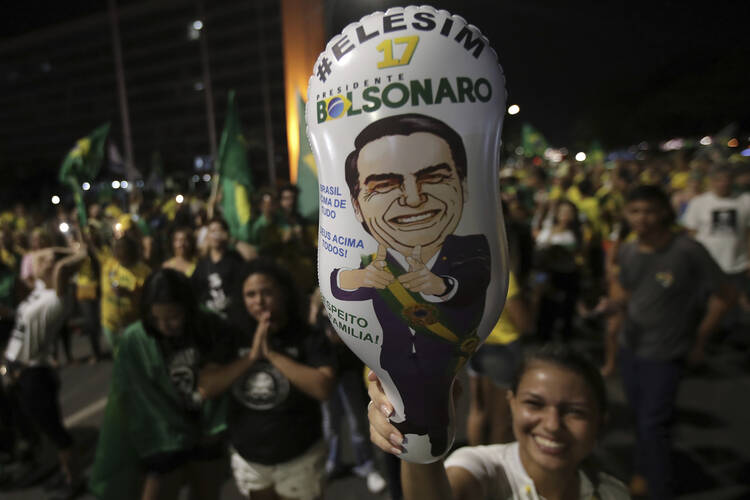 A supporter holds a balloon with the image of presidential candidate Jair Bolsonaro, during celebration in front of the National Congress, in Brasilia, Brazil, on Oct. 28. (AP Photo/Eraldo Peres)