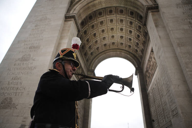 A military officer plays the original Armistice bugle from 1918 under the Arc de Triomphe on Nov. 11, 2018, in Paris. (AP Photo/Francois Mori, Pool)