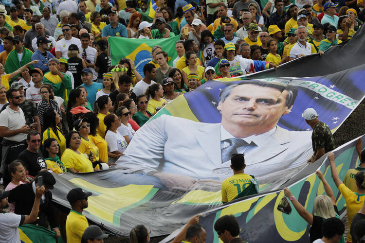 On Jan 1, supporters of Brazil's new President Jair Bolsonaro display a giant banner of him on his inauguration day in Brasilia, Brazil. (AP Photo/Silvia Izquierdo)