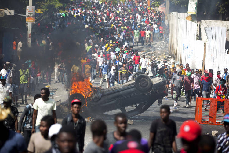 An overturned car burns during a protest demanding the resignation of Haitian President Jovenel Moise in Port-au-Prince, Haiti, on Feb. 12. (AP Photo/Dieu Nalio Chery)