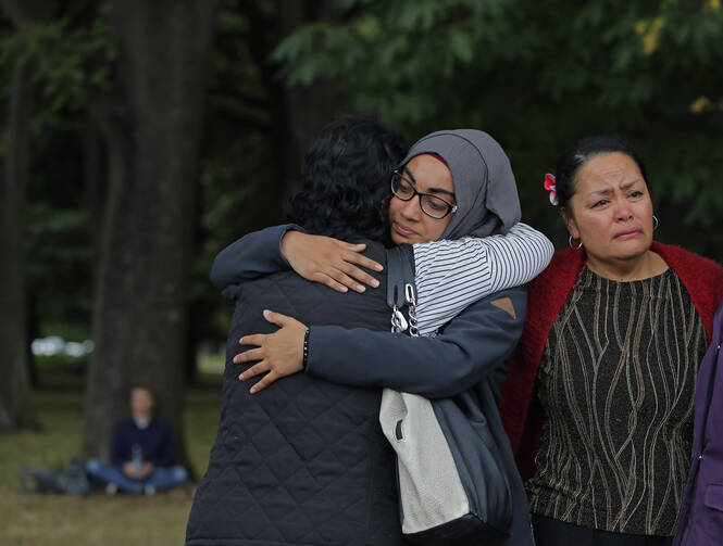 Mourners hug on March 18 after visiting the Masjid Al Noor mosque in Christchurch, New Zealand, the site of a terrorist attack last Friday. (AP Photo/Vincent Yu)