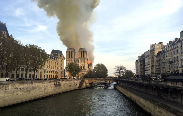 Notre Dame cathedral is burning in Paris, Monday, April 15, 2019. Massive plumes of yellow brown smoke is filling the air above Notre Dame Cathedral and ash is falling on tourists and others around the island that marks the center of Paris. (AP Photo/Lori Hinant)