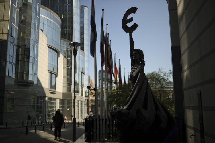 People walk past a sculpture with the Euro currency logo outside the European Parliament building in Brussels on May 15, 2019. Europeans from 28 countries will head to the polls May 23-26 to choose lawmakers to represent them at the European Parliament for the next five years. (AP Photo/Francisco Seco)