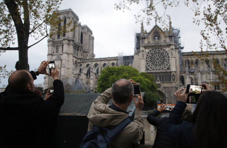 People take photos of the Notre Dame Cathedral in Paris, one day after a major blaze broke out at Paris' iconic cathedral. (AP Photo/Michel Euler, FILE)