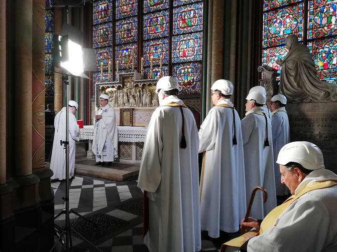 The Archbishop of Paris Michel Aupetit, second left, leads the first mass in a side chapel, two months after a devastating fire engulfed the Notre-Dame de Paris cathedral